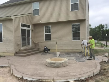 concrete patio with small fire pit and steps coming form back door