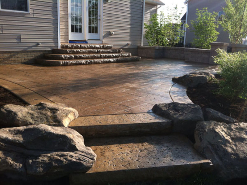 stamped concrete patio surrounded by boulders 