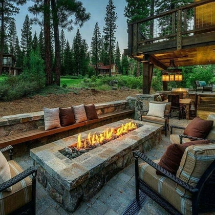 stone fire place surrounded by chairs in backyard patio